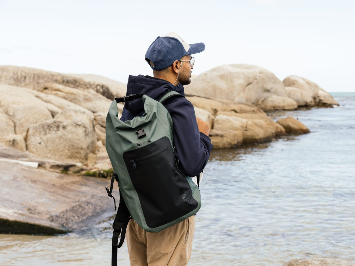 NSRI x Bound waterproof roll-top backpack worn on the rocks by the sea