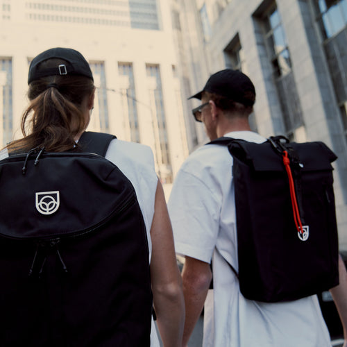Roll-Top Backpack in black worn on the back, side view with the mountains behind