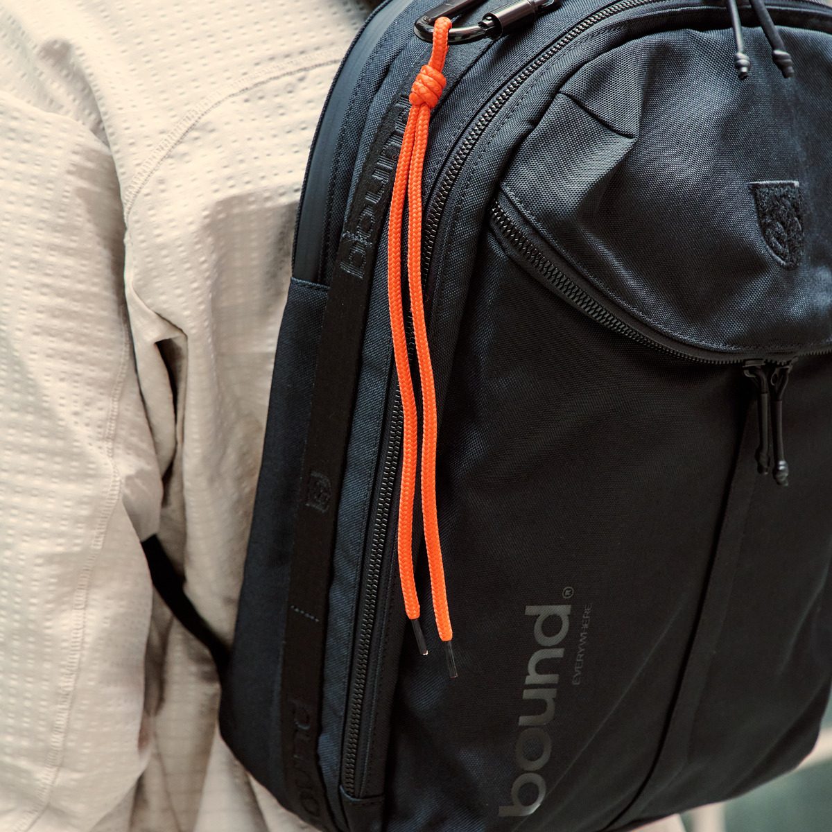 City Backpack Duffel in black close-up of the top handle, side zip and orange pull cord