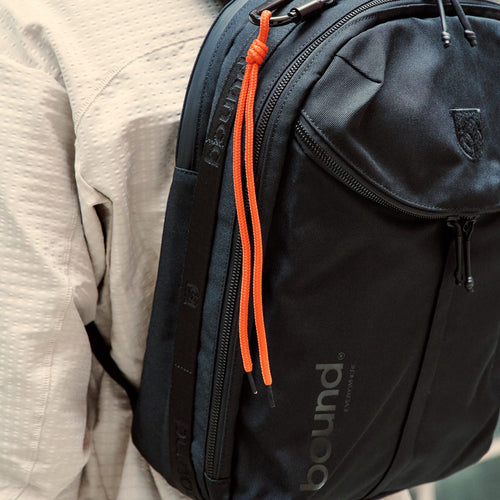 City Backpack Duffel in black close-up of the top handle, side zip and orange pull cord