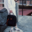 Town Backpack in black worn on the back, rear view by a woman on a city street