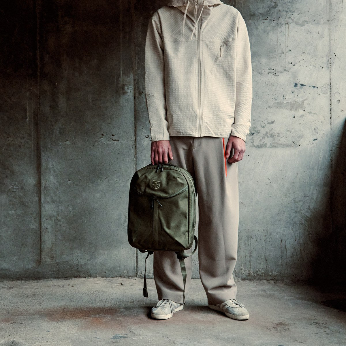 Town Backpack in green held up in front by a woman in sunglasses