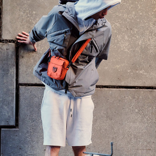 Town Sling Bag in black worn crossbody by a man in a white t-shirt on a city street