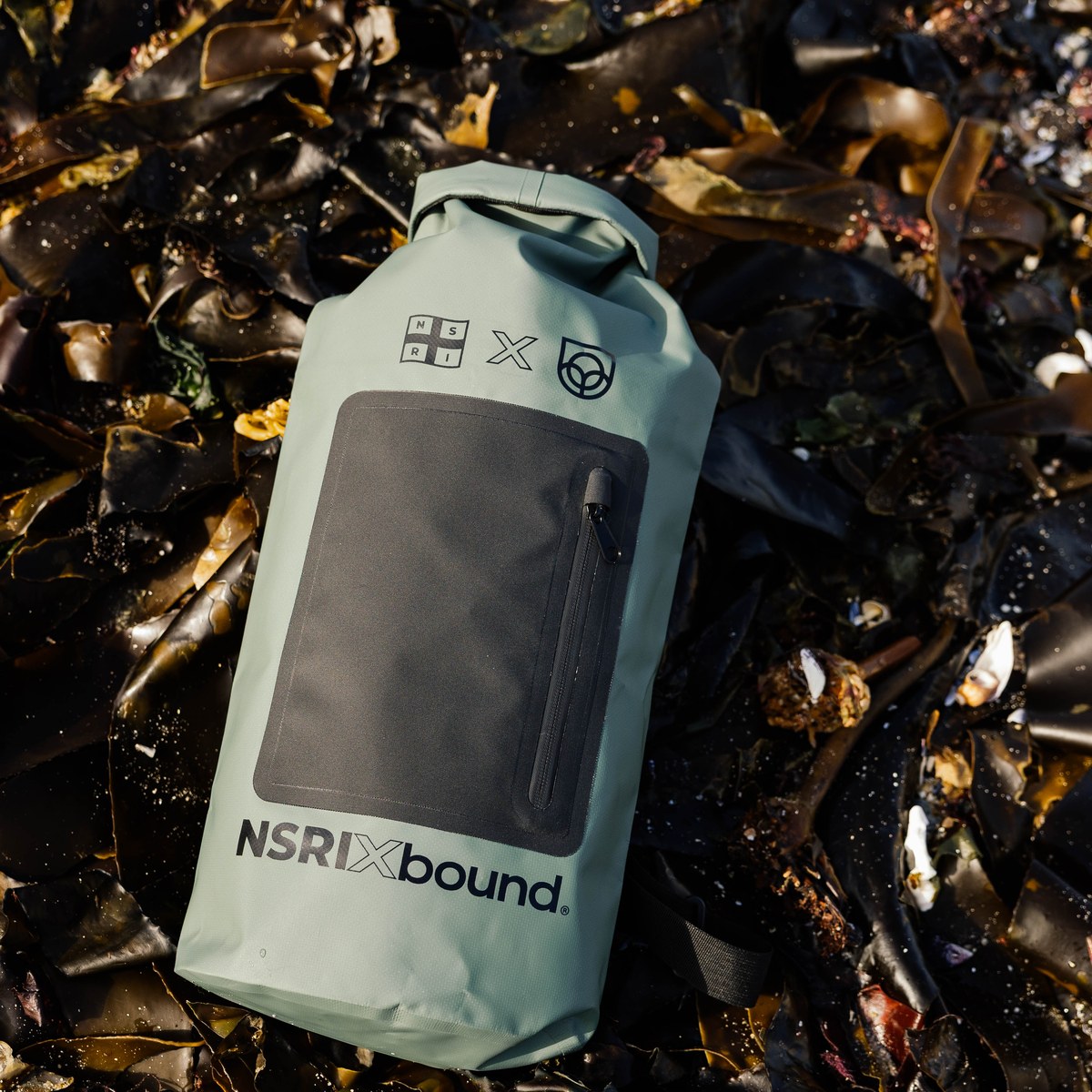 NSRI Grab Bag in green lying on a bed of kelp, roll-top closed