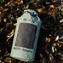 NSRI Grab Bag in green lying on a bed of kelp, roll-top closed