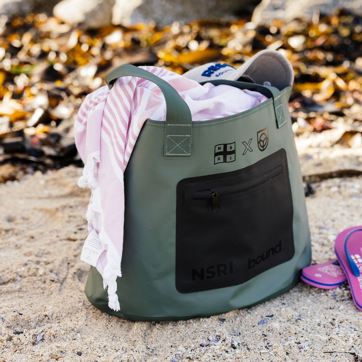 NSRI Tote in green on the beach with a towel and flip-flops beside it
