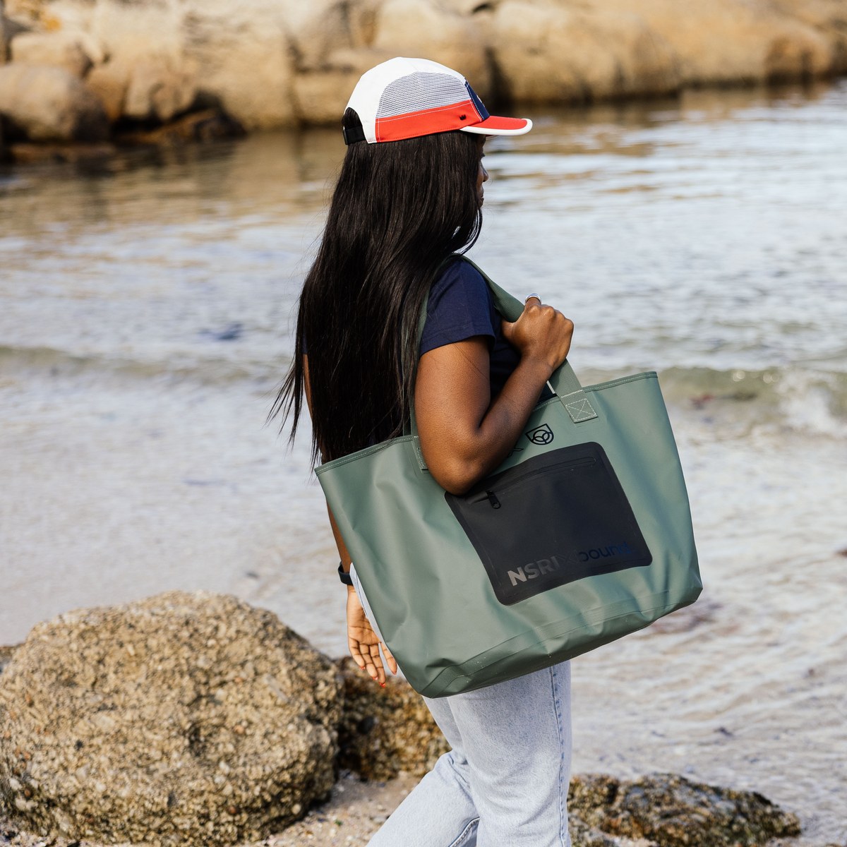 NSRI Tote in green carried on the shoulder by a woman walking along the shore