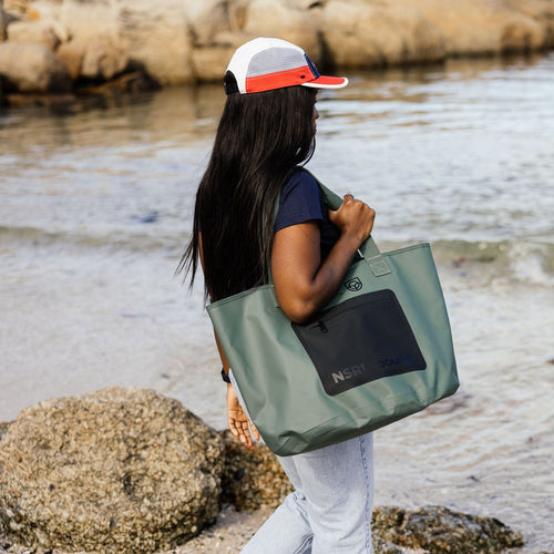 NSRI Tote in green carried on the shoulder by a woman walking along the shore