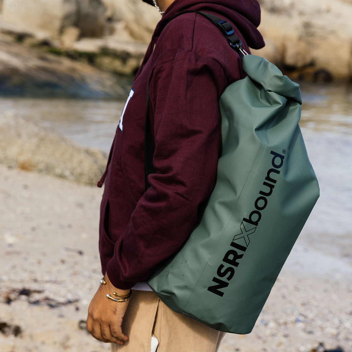 NSRI Backpack in green worn on the back by a man in a cap at the coast, side view