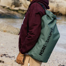 NSRI Backpack in green worn on the back by a man in a cap at the coast, side view