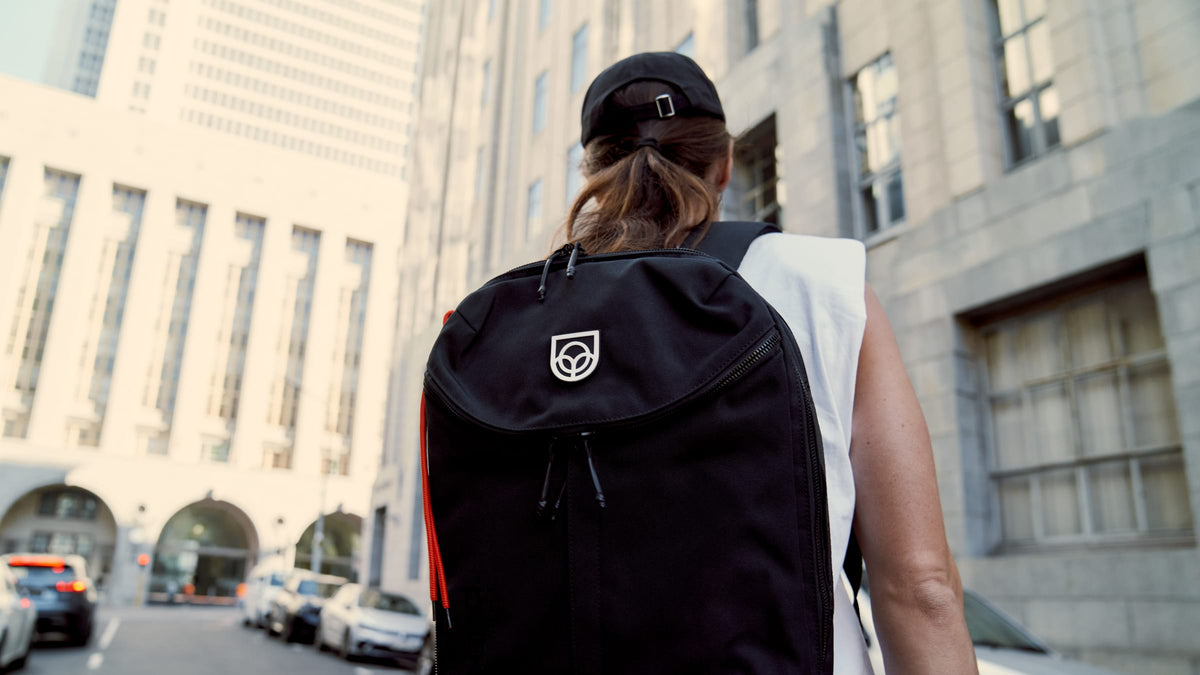 Commuter wearing a black Bound backpack with orange zip on a Cape Town street