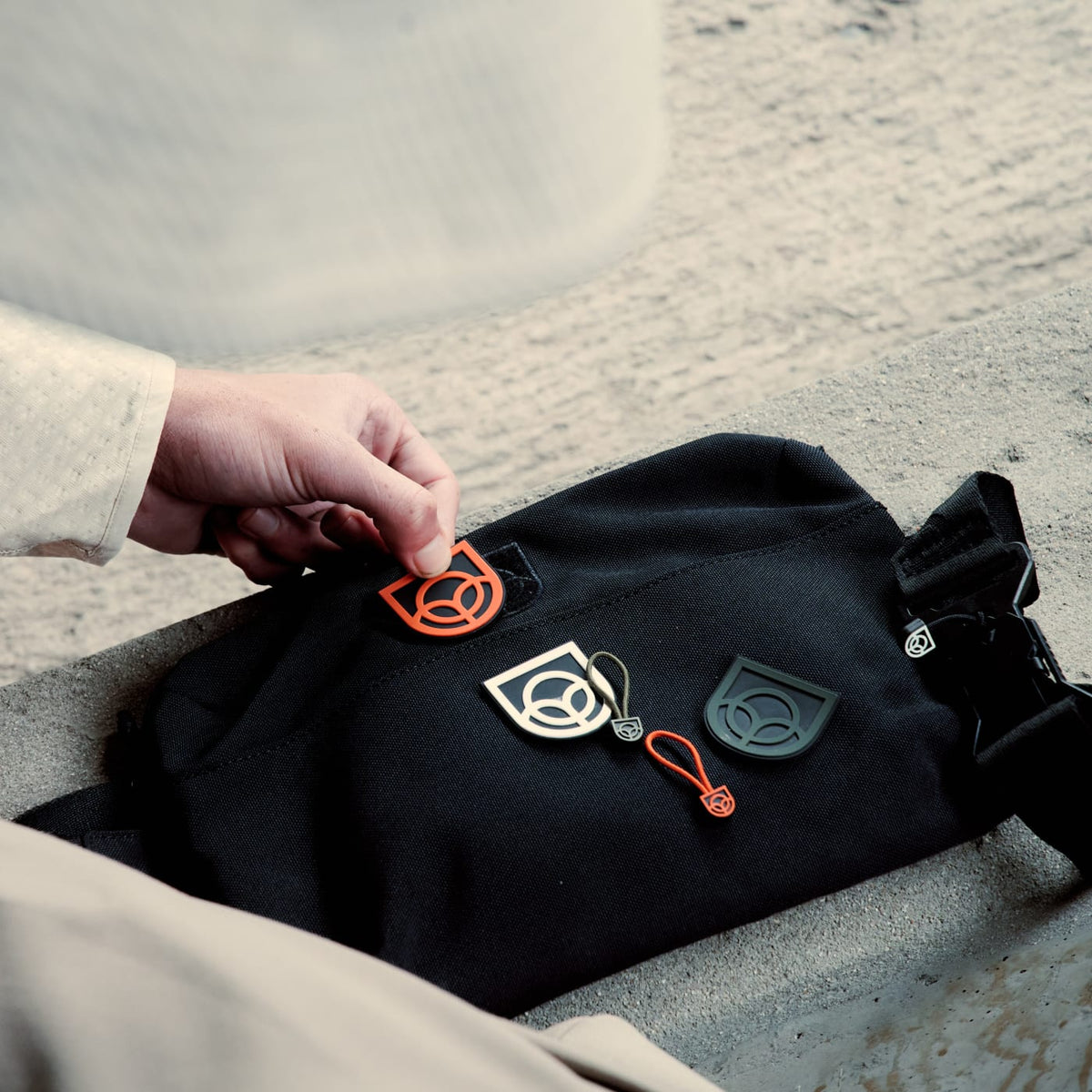 Hands swapping the removable Velcro colour patch on a black Bound bag